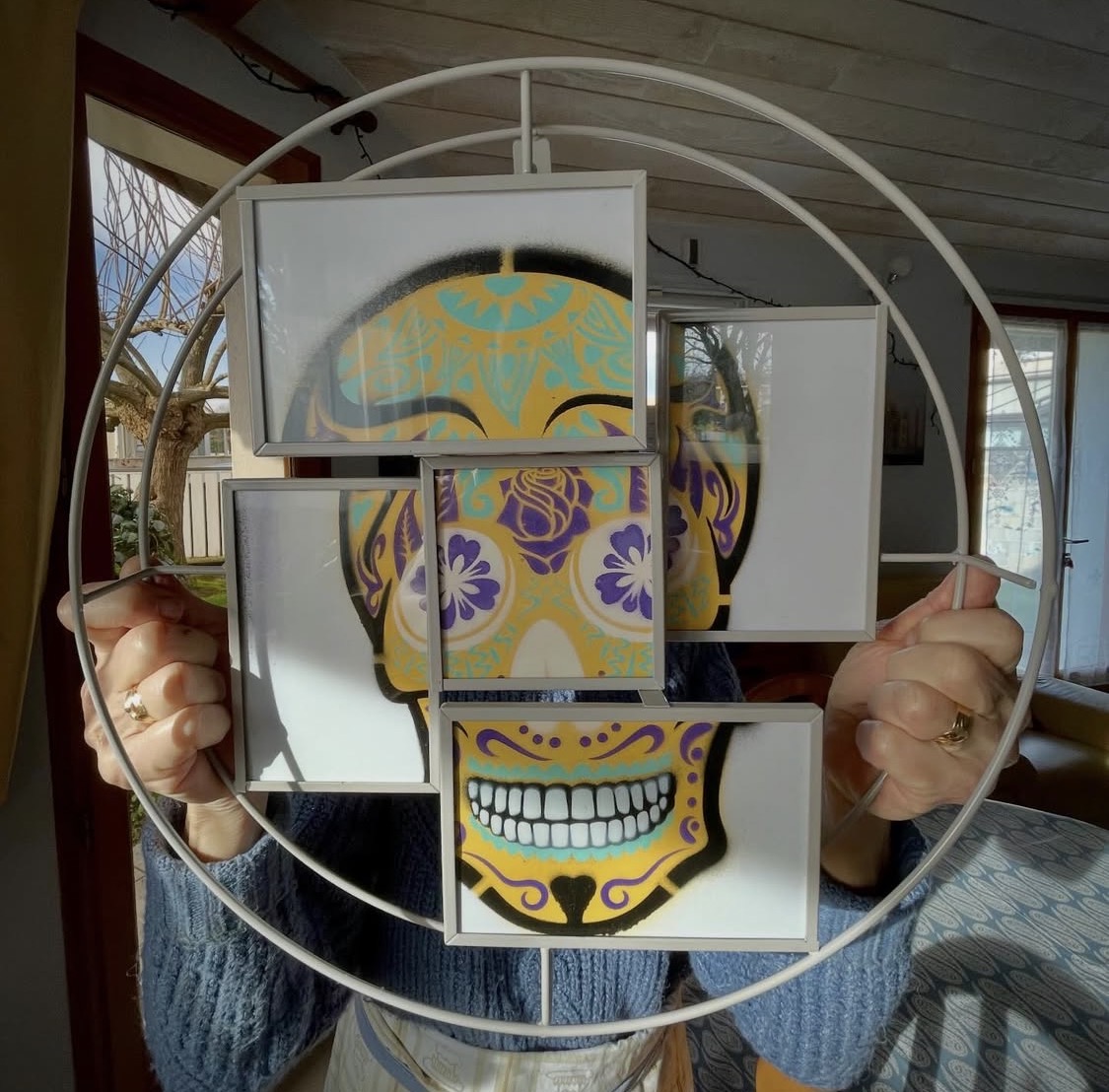 Calavera jaune et turquoise recomposée dans des cadres tenus à la main