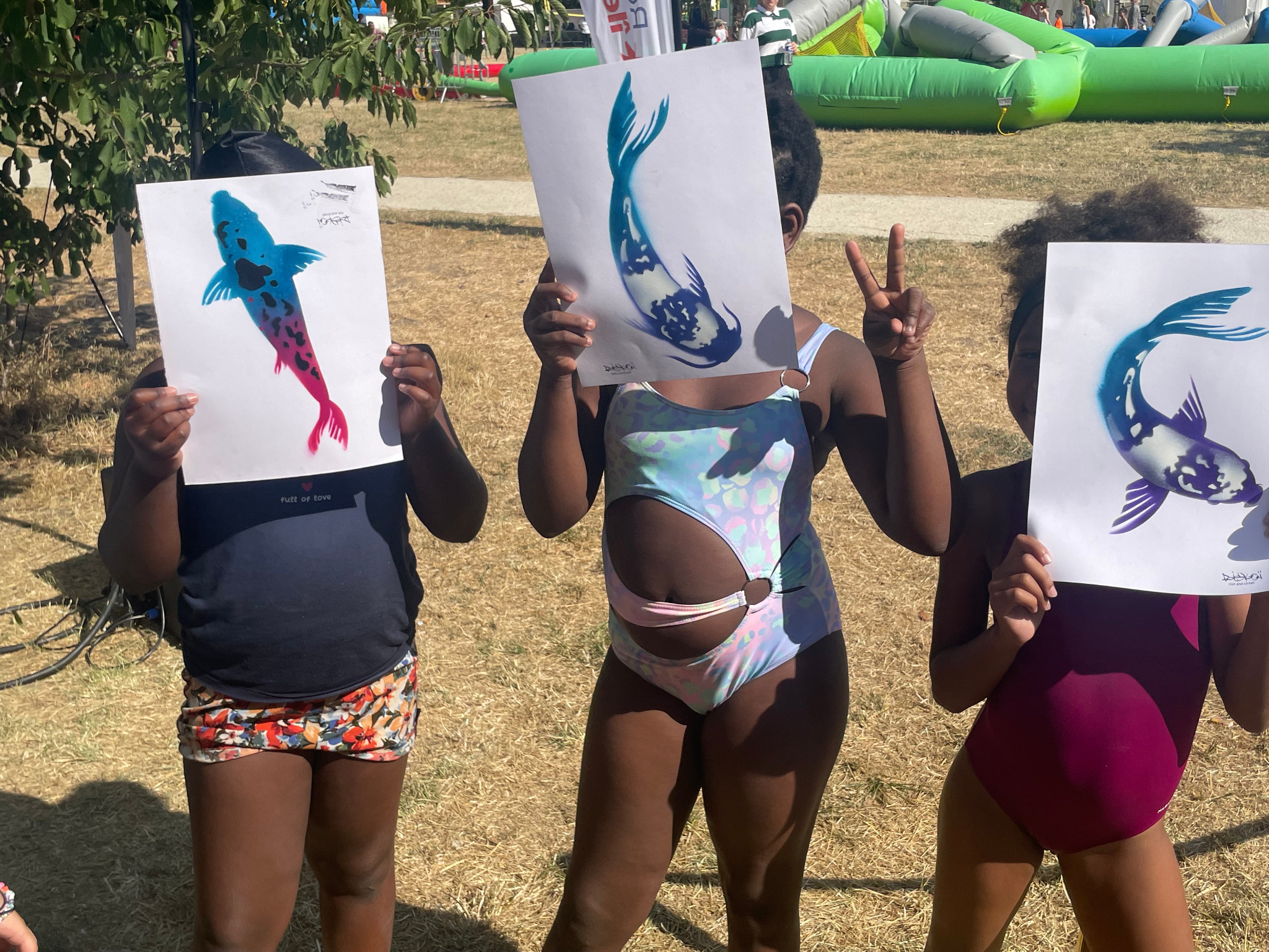 Trois enfants montrent leurs poissons colorés réalisés au pochoir